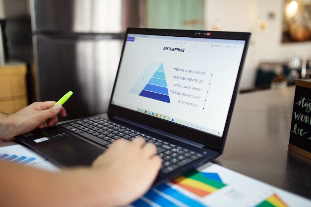 person-using-black-laptop-computer-7948005 Person analyzes business data on laptop, using pyramid chart and financial reports.